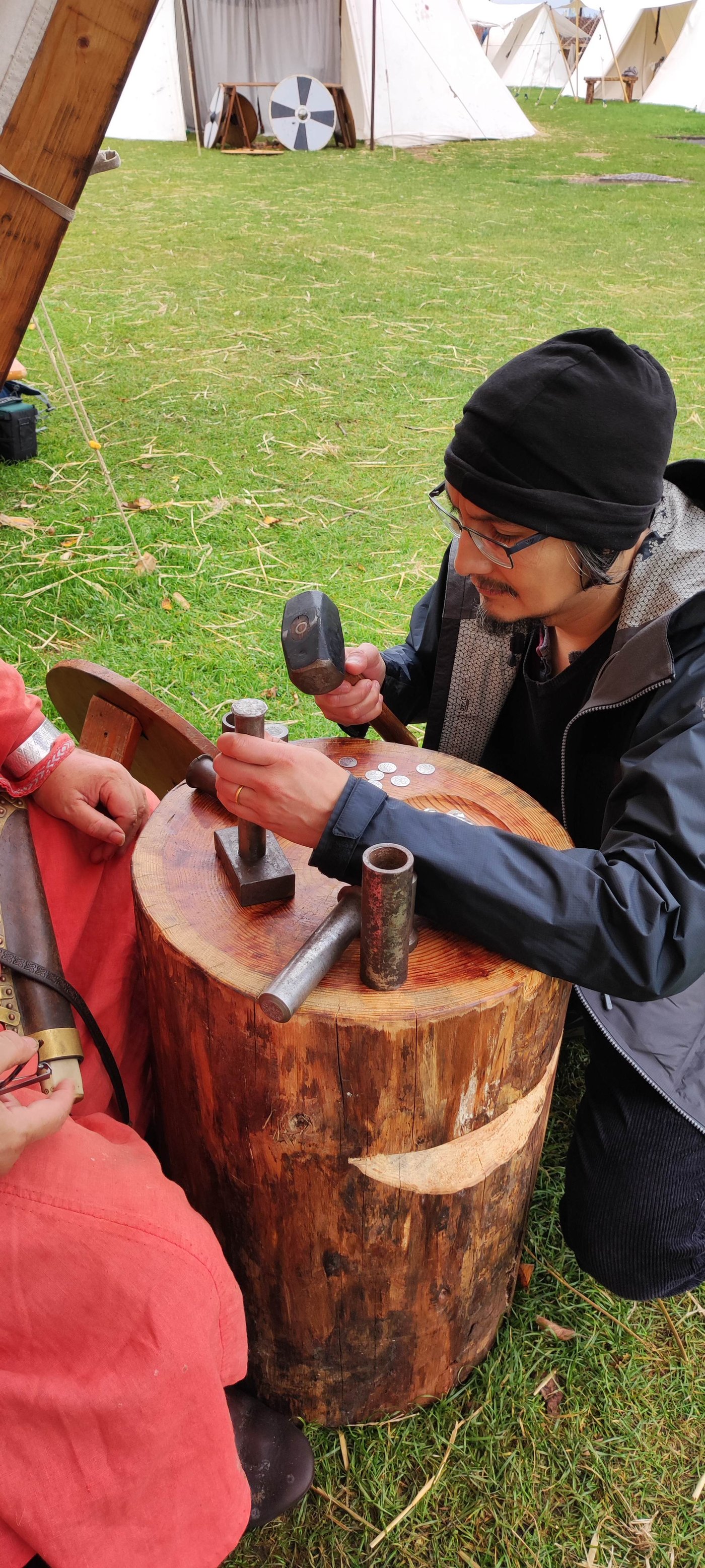 Me striking a coin with a hammer and die on the wooden block, under the coin-masters' guidance