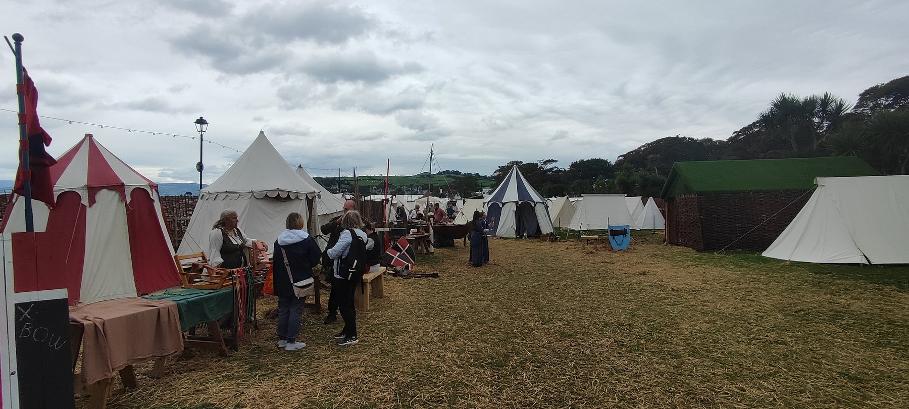 Reenactors' encampment at the Largs Viking Village, with striped market tents, a crossbow demonstration stall, and a small boat