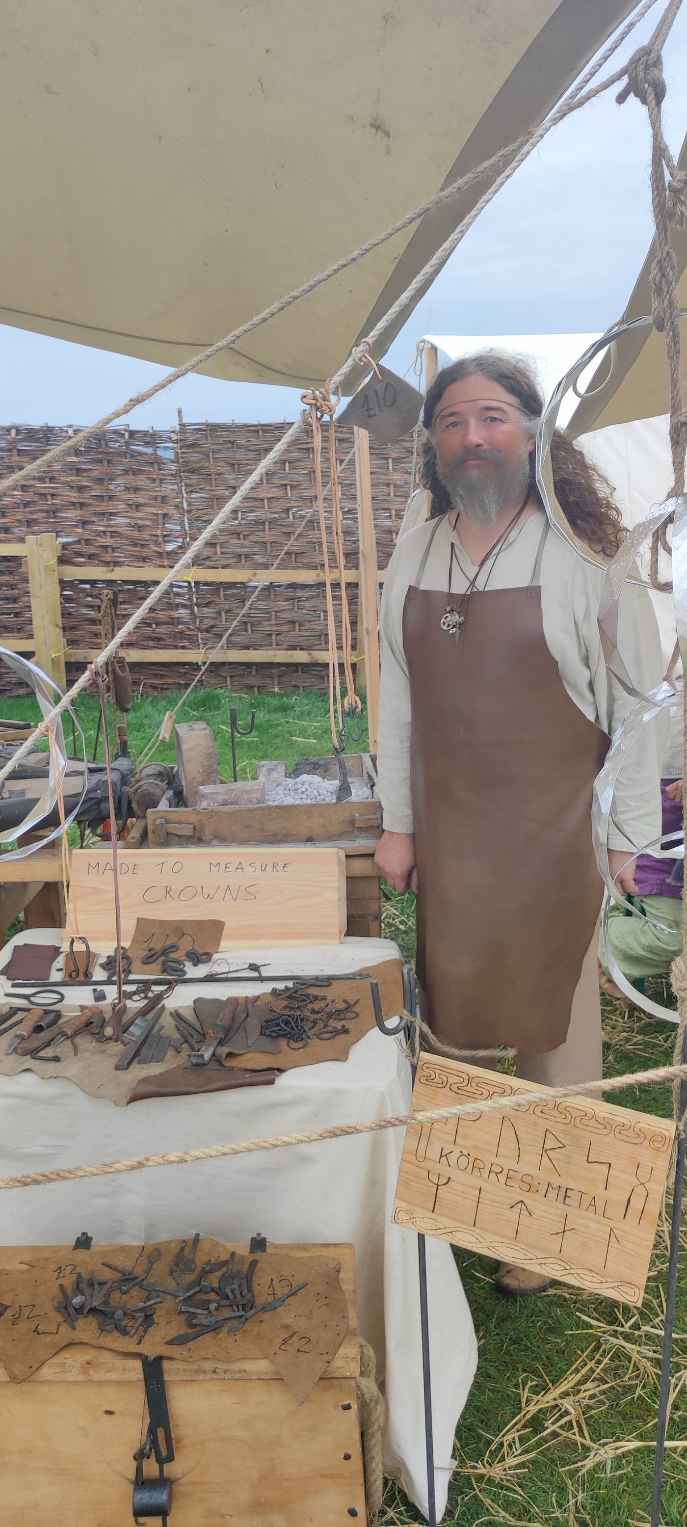The smith at the Körres Metal stall, in leather apron, standing next to his forge and tools